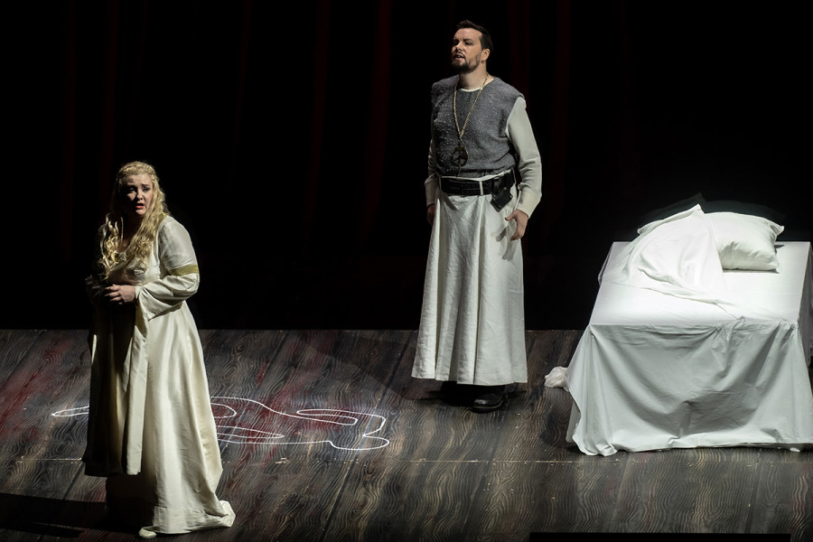 Lohengrin - © Bettina Stöß Lohengrin und Elsa sind nun alleine im Brautgemach. Die Situation zwischen beiden wirkt angespannt. Auf dem Boden neben dem Bett ist mit Kreide der Umriss einer Leiche, wie bei einer Tatortsicherung.
