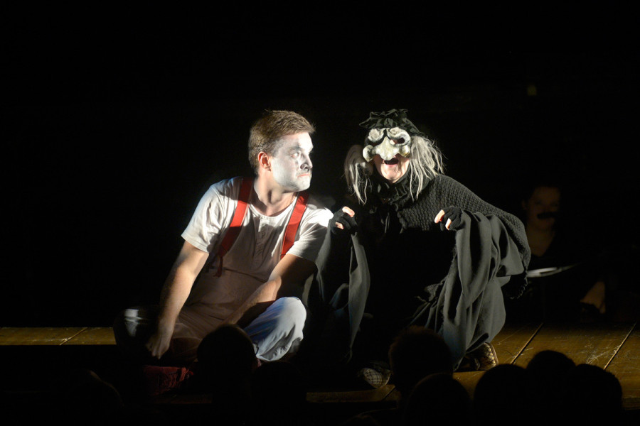 Die Zauberflöte - © Bettina Stöß Im Gespräch vertieft sitzen Papageno und Papagena auf der Passerelle. Papageno mit seinem weißen T-Shirt und den roten Hosenträgern, Papagena trägt noch Maske und Mantel der alten Frau, in die sie noch verwandelt ist.