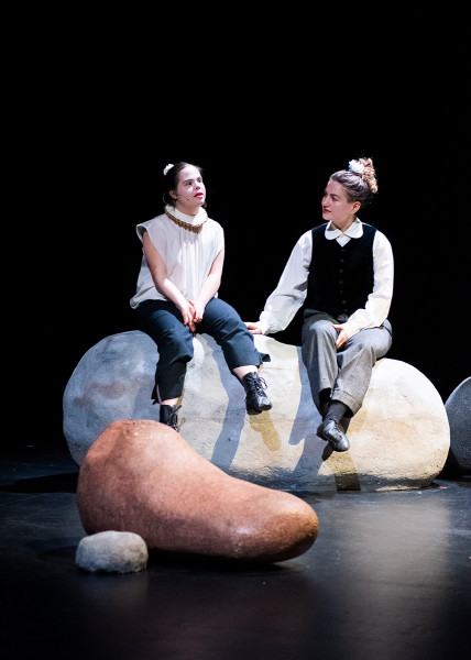 Zwei Darstellerinnen des Jungen Ensembles "Stabat Mater" sitzen auf Steinen ...