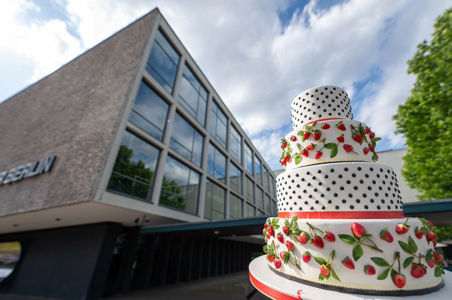 Guilty pleasures - © Motiv: Georg Roither Eine zuckrige mehrstöckige Sahnetorte ragt vor der Fassade der Deutschen Oper Berlin auf. Dieses Motiv illustriert das Kammerkonzert "Quilty pleasures" mit Schnulzen und musikalischem Kitsch.