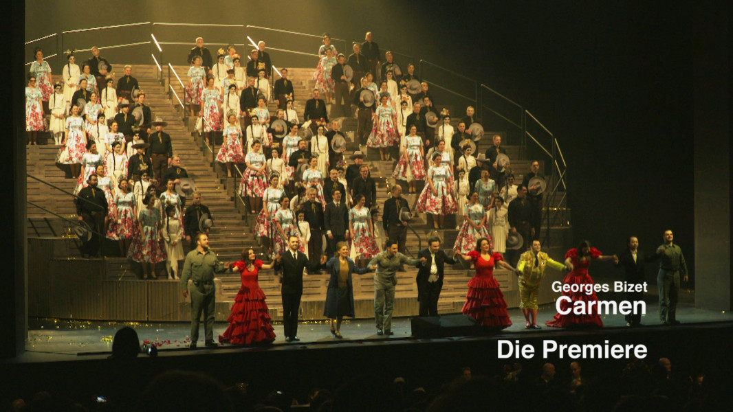 Dieses Foto ist das Startbild für ein Video mit Publikumsstimmen zur Premiere. Auf dem Foto der Chor der Deutschen Oper Berlin und die Darsteller*innen der Produktion beim Schlussapplaus.