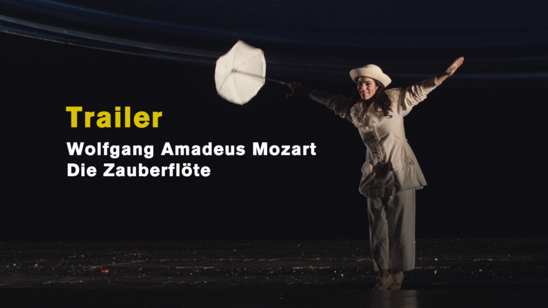 Wolfgang Amadeus Mozart: Die Zauberflöte (2019) - © Ruth Tromboukis Dieses Bild ist das Startbild zu unserem Stück-Trailer. Papagena in einem weißen Clownsgewand mit einem kleinen weißen Hütchen und einem Schirmchen tänzelt nach vorne.