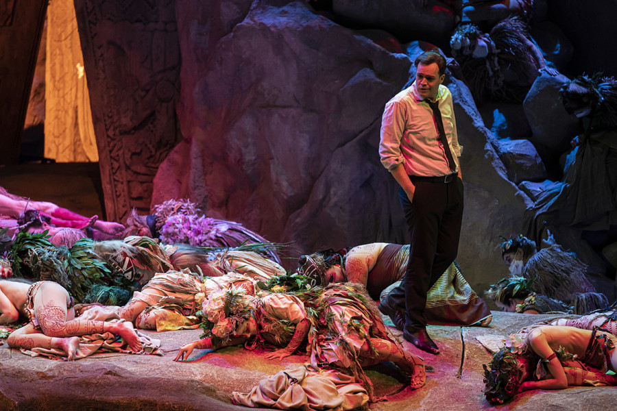 Parsifal - © Bettina Stöß Die Blumenmädchen haben sich von ihren aschegrauen Mänteln befreit. Mit bunten Blumen und südseehaften Tattoos liegen sie am Boden. Zwischen ihnen steht Parsifal.
