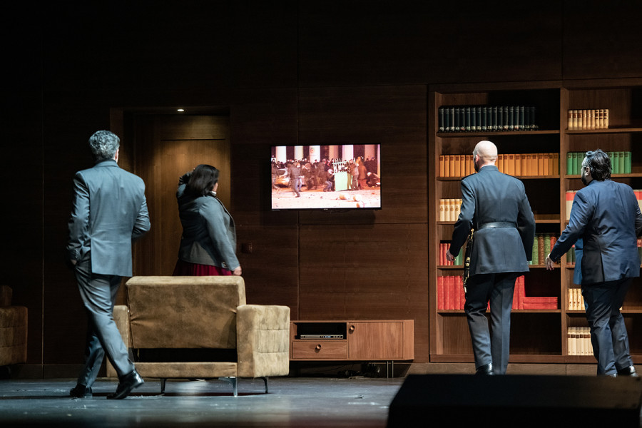 Simon Boccanegra - © Bettina Stöß Paolo Albiani, Amelia, Boccanegra und Gabriele Adorno beobachten auf einem Bildschirm die bürgerkriegsähnlichen Kämpfe in den Straßen Genuas.