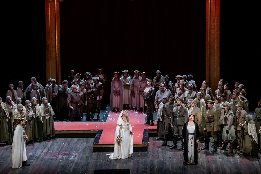 Lohengrin - © Bettina Stöß Vor dem Einzug ins Münster: Im Brautgewand wendet sich Elsa gegen Ortrud. Diese provoziert einen Eklat. Das brabantische Volk schaut irritiert auf diese Situation.