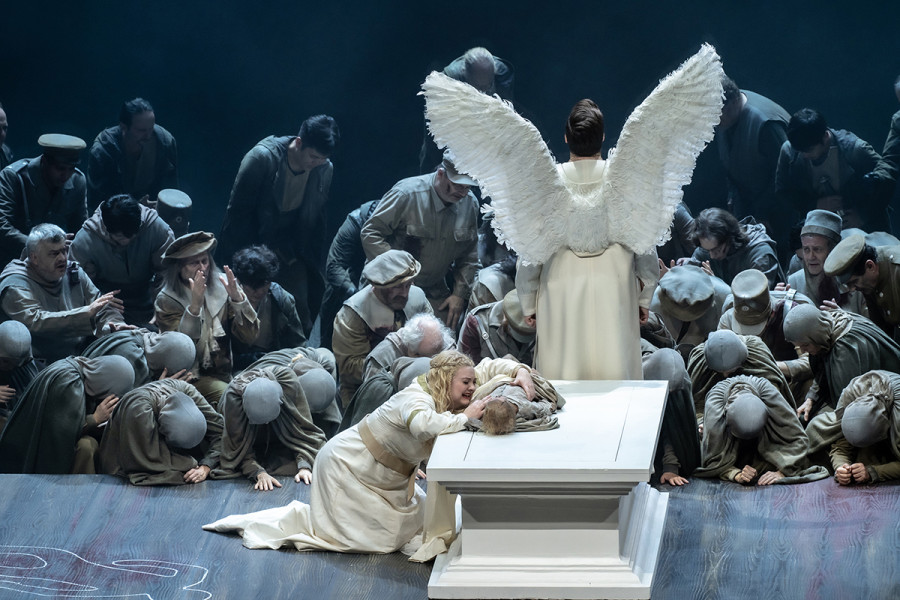 Lohengrin - © Bettina Stöß Die Leiche des Bruders liegt auf dem Sarkophag, Elsa kniet weinend davor und hält den kleinen Jungen im Arm. Lohengrin steht abgewandt zum Heer.