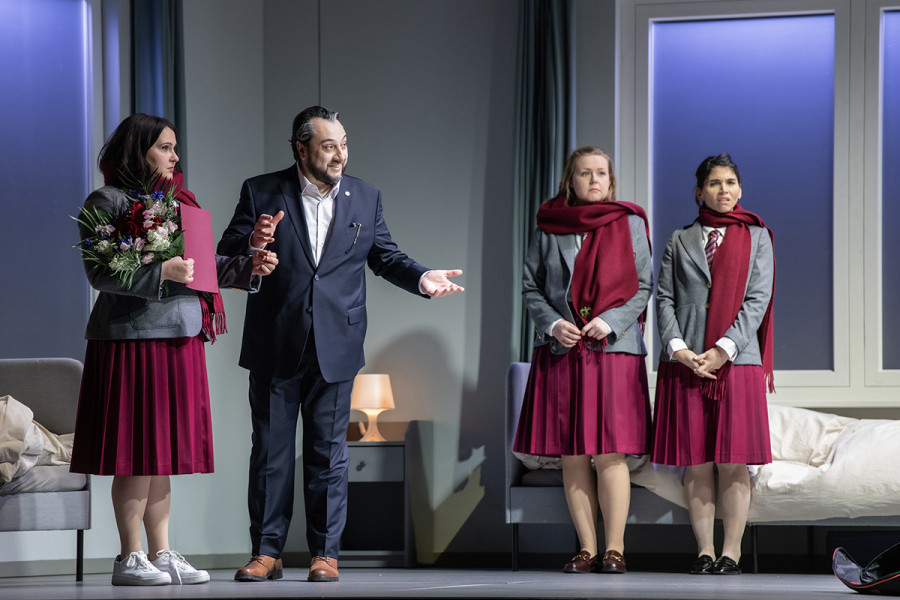 Simon Boccanegra - © Bettina Stöß Der Vater Boccanegra findet in Amelia / Maria seine verloren geglaubte Tochter. Sie hält einen Blumenstrauß und eine rote Mappe im Arm. Neben Vater und Tochter zwei Schulfreundinnen der Amelia.