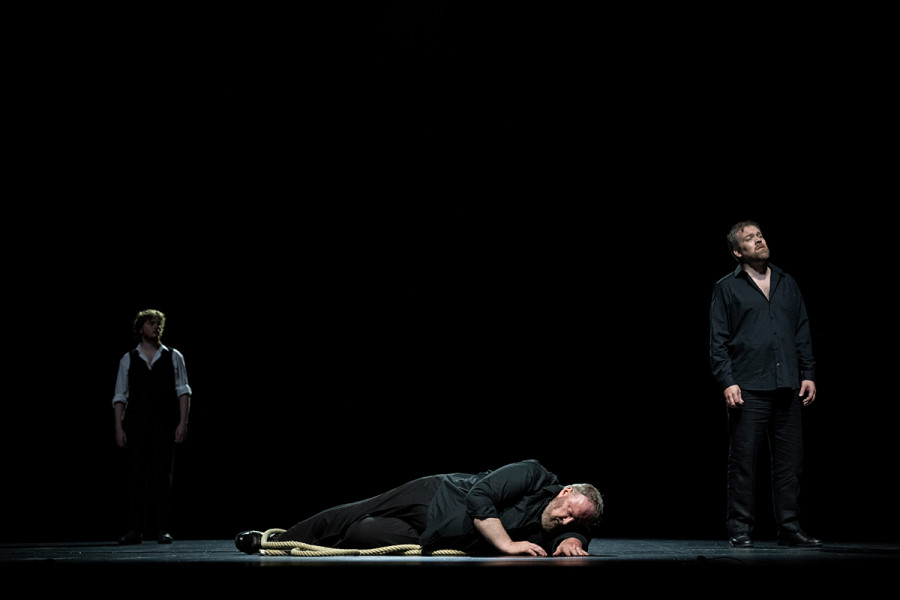 Tristan und Isolde - © Carole Parodi Eine Szenenimpression aus Thalheimers TRISTAN UND ISOLDE: Die Bühne ist schwarz. Vorne am Boden liegend Tristan, hinter ihm Kurwenal.