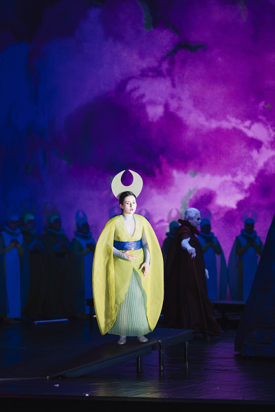 Vor einem dramatischen, lilafarbenen Himmel steht Suor Angelica in ihrem goldgelben Mantel.