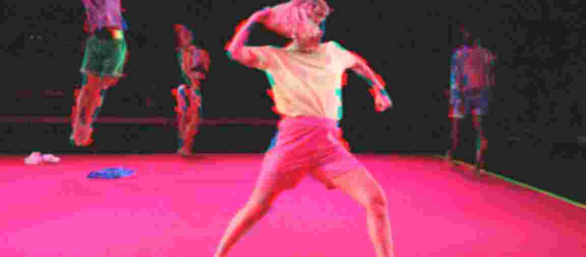 Es sind 4 Tänzer:innen in dynamischen Bewegungen auf einem pinken Teppichboden zu sehen. Es sind 4 Tänzer:innen in dynamischen Bewegungen auf einem pinken Teppichboden zu sehen.