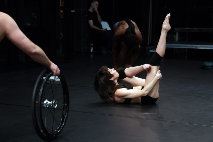 Eine Tänzerin liegt auf dem Boden und streckt ein Bein senkrecht nach oben. 