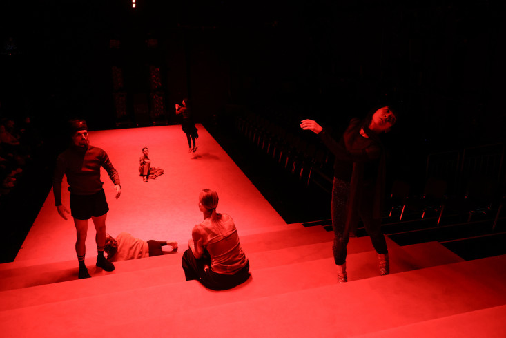 Ein großer roter Teppich zieht sich über die ganze Bühne und die Treppen hoch in den Zuschauerraum. Auf ihm stehen, sitzen, liegen und tanzen sechs Personen.