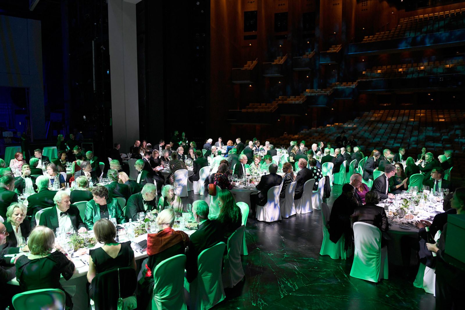 Auf dem Foto eine Impression aus einem Bühnendinner. Auf der Hauptbühne speisen die Mitglieder Förderkreises mit Blick in den stimmungsvoll beleuchteten Saal.