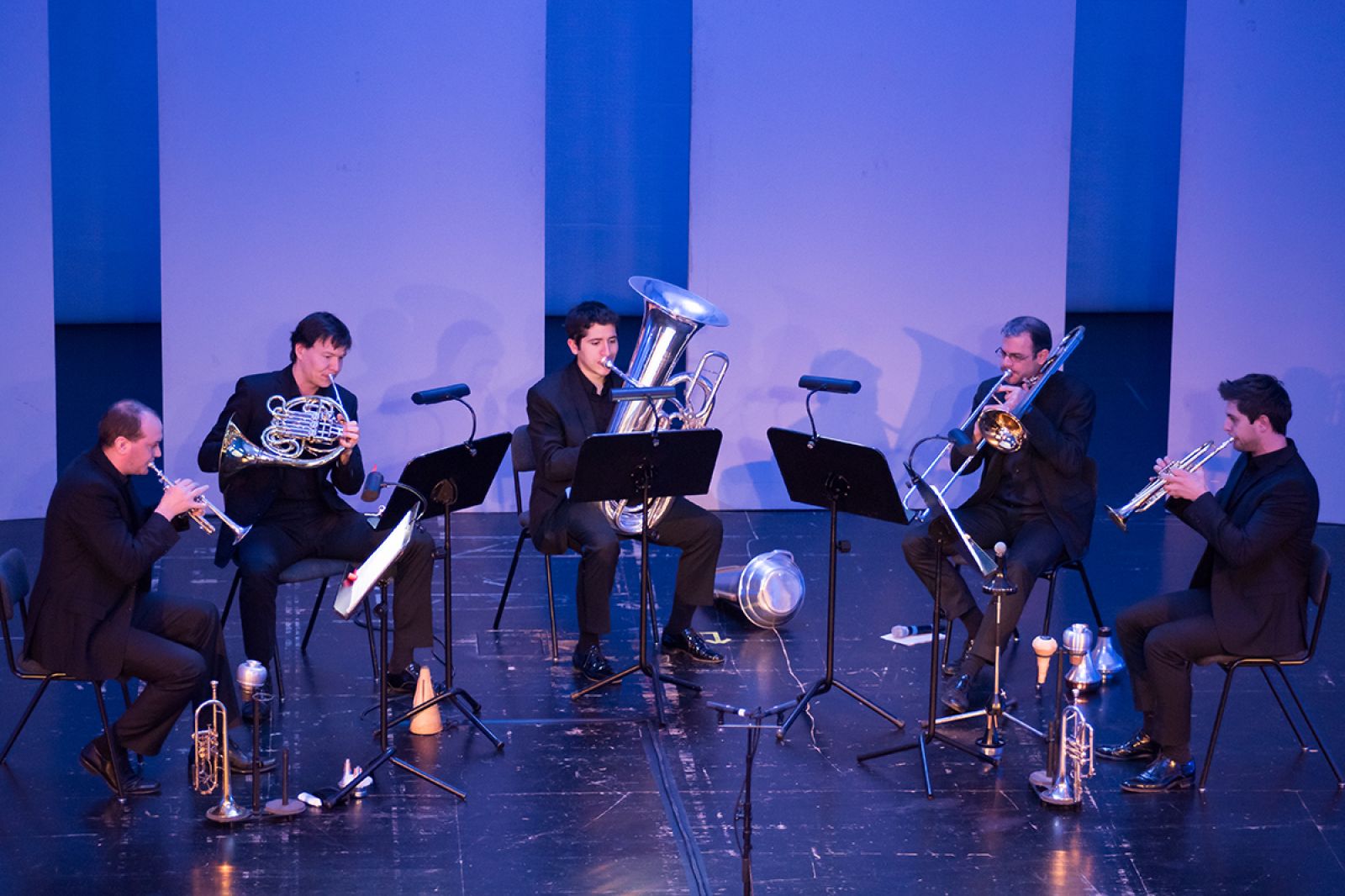 Auf dem Foto ein Blechbläserensemble(zwei Trompeten, Horn, Tuba und Posaune) während eines Kammerkonzertes in der Tischlerei.