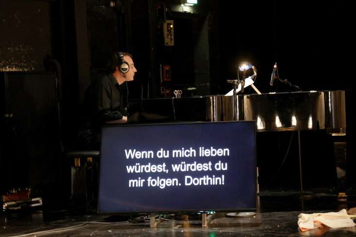 Ein Mann mit Kopfhörern am Klavier. Vor ihm ein Monitor mit dem Text, der gesungen wird. Ein Mann mit Kopfhörern am Klavier. Vor ihm ein Monitor mit dem Text, der gesungen wird.