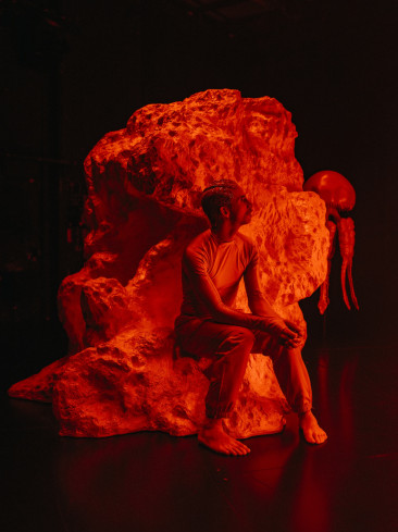 © Philip Frowein | Eine Person sitzt auf einer Art Felsen. Alles ist in rotes Licht getaucht. Im Hintergrund steht eine Qualle. Eine Person sitzt auf einer Art Felsen. Alles ist in rotes Licht getaucht. Im Hintergrund steht eine Qualle.