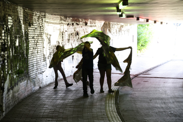 In einem Tunnel sind vier Personen zu sehen. Sie schwenken große Tücher. In einem Tunnel sind vier Personen zu sehen. Sie schwenken große Tücher.