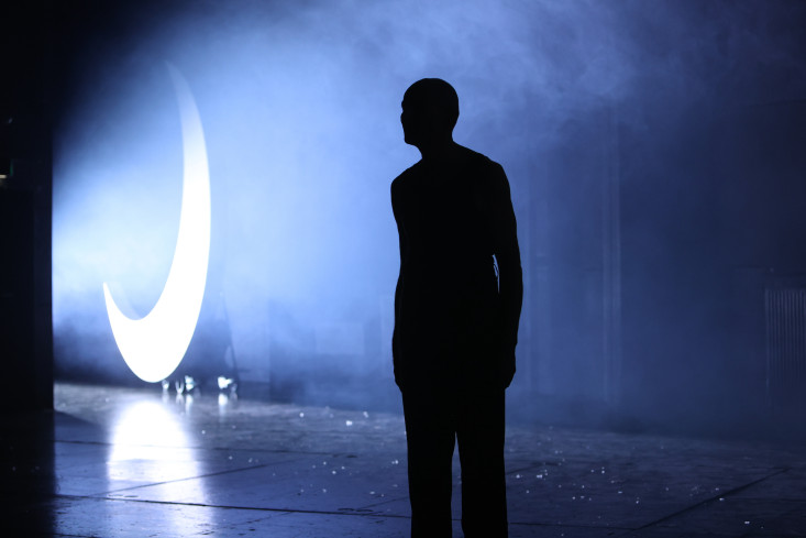 Vorn ist die Silhouette eines Mannes. Im Hintergrund steht eine hellangestrahlte Mondsichel. Das Licht ist bläulich. Es ist Nebel auf der Bühne. Vorn ist die Silhouette eines Mannes. Im Hintergrund steht eine hellangestrahlte Mondsichel. Das Licht ist bläulich. Es ist Nebel auf der Bühne.
