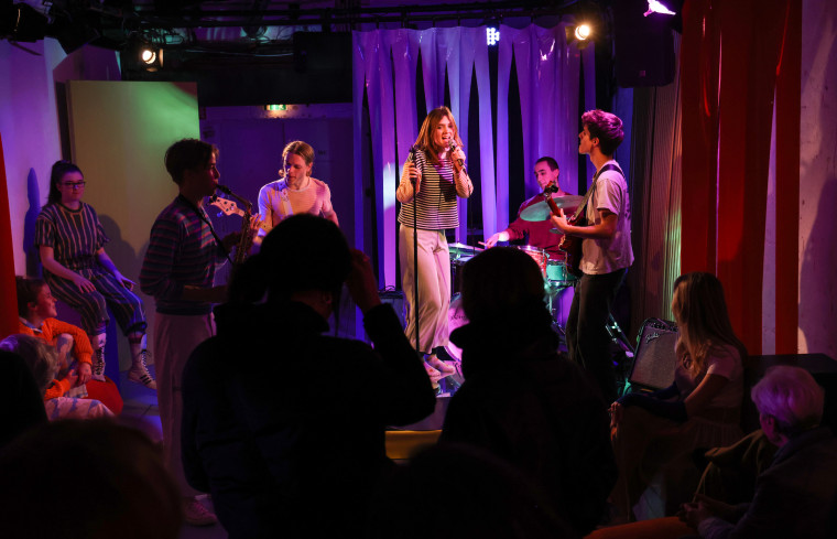 Eine Band spielt auf einer kleinen Bühne. Das Publikum steht davor. Eine Band spielt auf einer kleinen Bühne. Das Publikum steht davor.