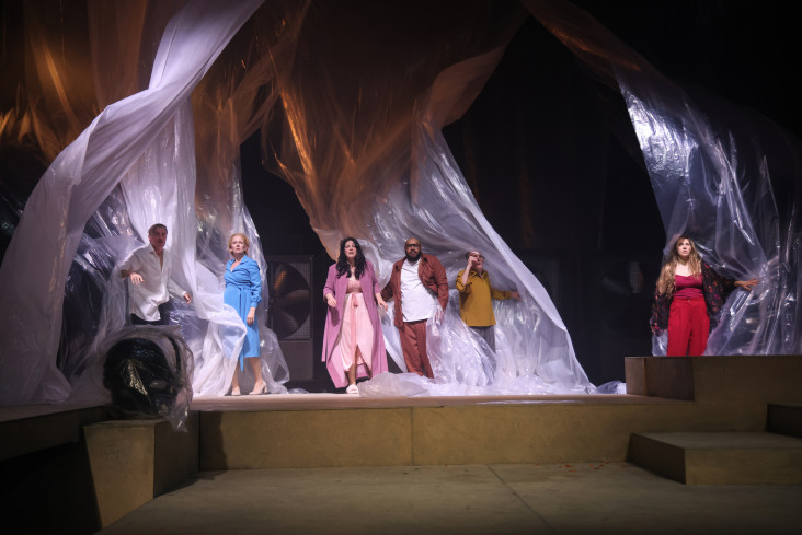 Sechs Personen stehen auf der Bühne. Alle blicken nach oben. Hinter ihnen flattern große Folien. Sechs Personen stehen auf der Bühne. Alle blicken nach oben. Hinter ihnen flattern große Folien.