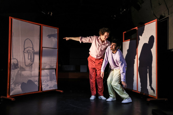 Zwei Personen stehen nebeneinander. Die eine Person zeigt auf eine Wand. Auf die Wand ist eine Zeichnung projiziert. Zwei Personen stehen nebeneinander. Die eine Person zeigt auf eine Wand. Auf die Wand ist eine Zeichnung projiziert.