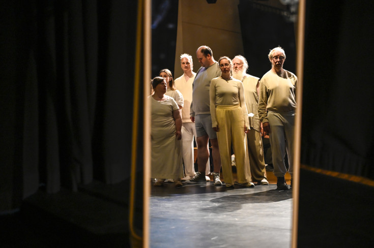 © Manja Herrmann | Links und rechts stehen Stellwände. In der Mitte sind sieben Personen. Sie sind alle weiß angezogen und stehen nebeneinander. Links und rechts stehen Stellwände. In der Mitte sind sieben Personen. Sie sind alle weiß angezogen und stehen nebeneinander.