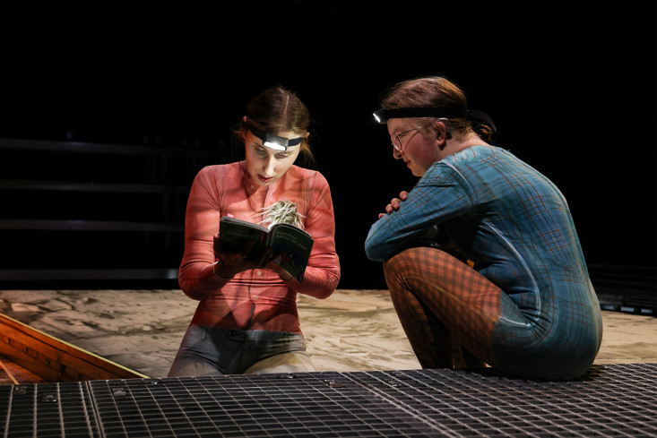 Zwei Schauspielerinnen schauen auf ein Buch. Beide tragen Stirnlampen. Zwei Schauspielerinnen schauen auf ein Buch. Beide tragen Stirnlampen.