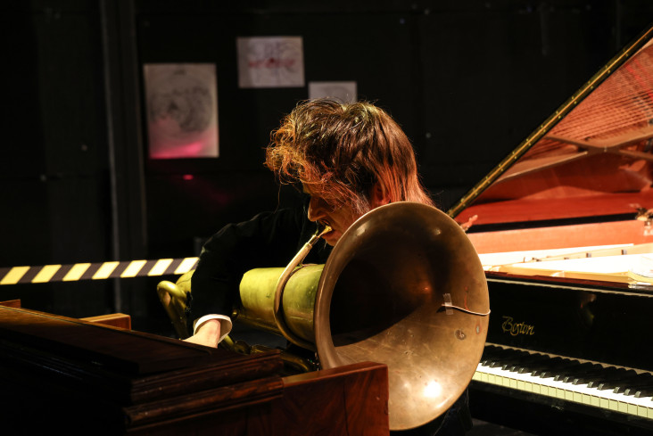 Ein Musiker spielt Tuba. Hinter ihm steht ein Flügel.