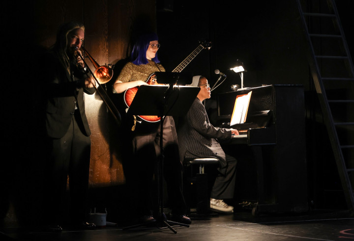 Die Band spielt Musik. Um sie herum ist es dunkel. Eine Person sitzt am Klavier, eine andere spielt Bass, einer Posaune. Die Band spielt Musik. Um sie herum ist es dunkel. Eine Person sitzt am Klavier, eine andere spielt Bass, einer Posaune.