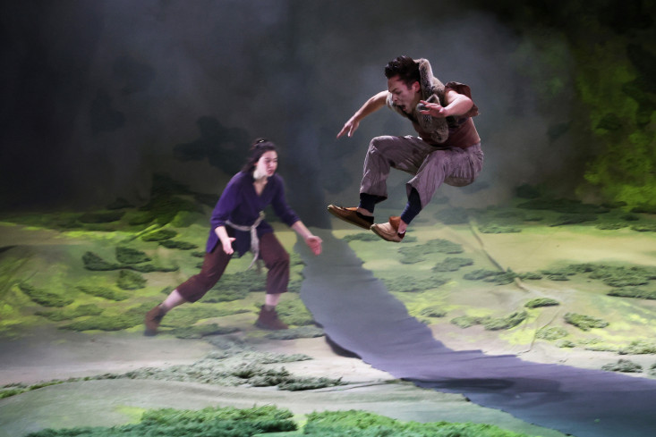 Ein Schauspieler springt und ist mitten im Flug hoch in der Luft. Eine Schauspielerin nimmt Anlauf um ebenfalls zu springen. Ein Schauspieler springt und ist mitten im Flug hoch in der Luft. Eine Schauspielerin nimmt Anlauf um ebenfalls zu springen.