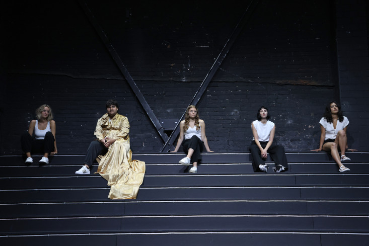 Fünf Jugendliche sitzen auf einer Treppe nebeneinander.