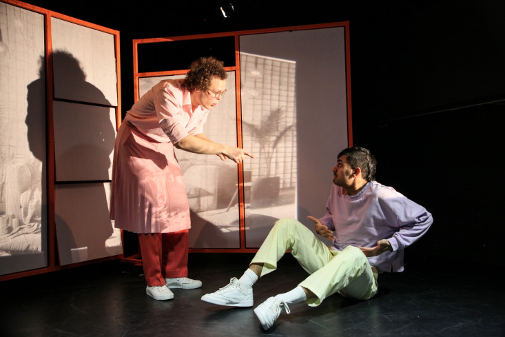 Ein Schauspieler sitzt auf dem Boden. Neben ihm steht ein Sänger. Er beugt sich etwas zu ihm herunter und zeigt mit dem Finger auf ihn. Ein Schauspieler sitzt auf dem Boden. Neben ihm steht ein Sänger. Er beugt sich etwas zu ihm herunter und zeigt mit dem Finger auf ihn.