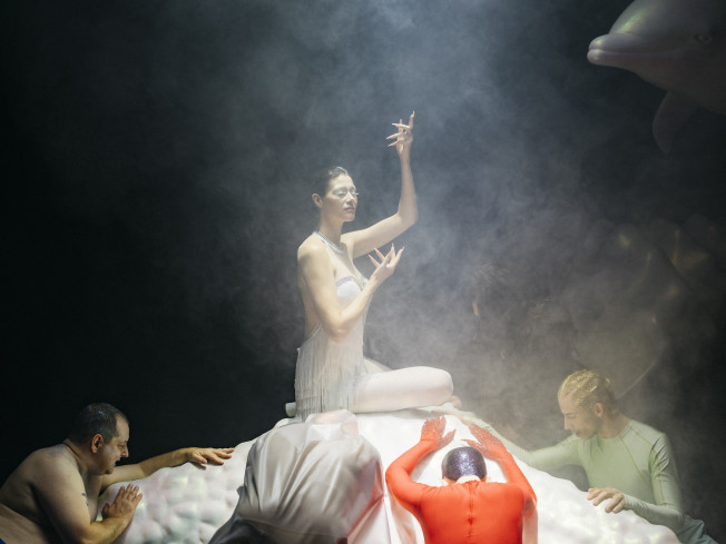 © Philip Frowein | Nebel ist auf der Bühne. In der Mitte sitzt eine weißgekleidete Schauspielerin auf einer weißen Erhöhung. Um sie herum sind vier andere Personen. Alle verneigen sich. Nebel ist auf der Bühne. In der Mitte sitzt eine weißgekleidete Schauspielerin auf einer weißen Erhöhung. Um sie herum sind vier andere Personen. Alle verneigen sich.