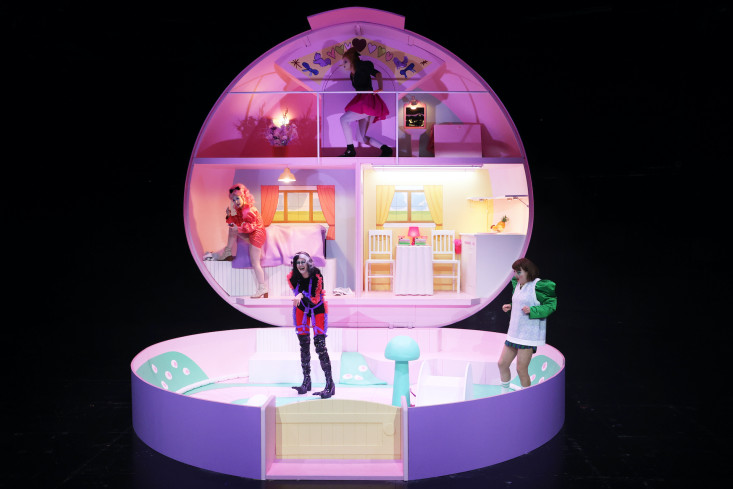Eine riesengroße Polly-Pocket-Schachtel ist das Bühnenbild. In ihr bewegen sich vier Personen wie Puppen in einem kleinen Puppenhaus. Eine riesengroße Polly-Pocket-Schachtel ist das Bühnenbild. In ihr bewegen sich vier Personen wie Puppen in einem kleinen Puppenhaus.