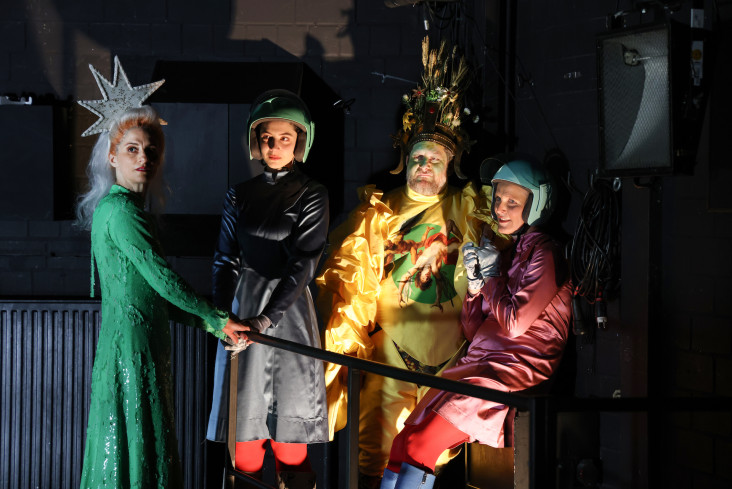 Vier Personen stehen eng beieinander. Alle tragen bunte Kostüme. Zwei haben einen Helm auf. Die beiden anderen tragen auffälligen Kopfschmuck. Vier Personen stehen eng beieinander. Alle tragen bunte Kostüme. Zwei haben einen Helm auf. Die beiden anderen tragen auffälligen Kopfschmuck.
