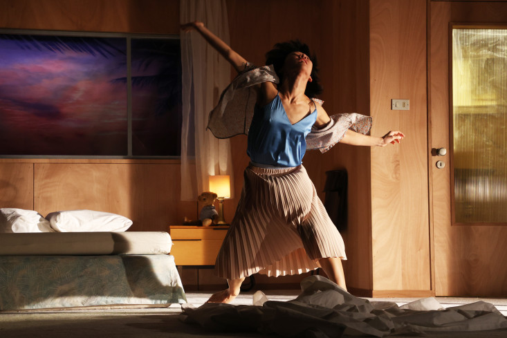 Eine Frau tanzt. Ihre Arme sind weit ausgebreitet. Sie steht in einem Hotelzimmer. Eine Frau tanzt. Ihre Arme sind weit ausgebreitet. Sie steht in einem Hotelzimmer.