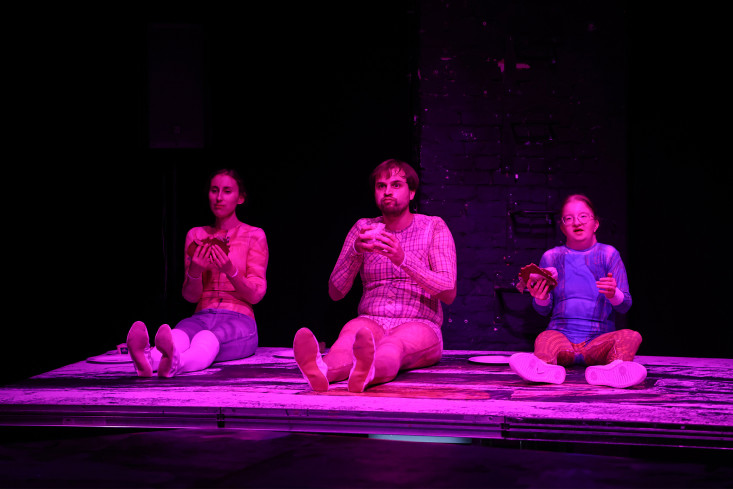 Drei Personen sitzen nebeneinaner. Zwei halten ein Butterbrot in den Händen.  Drei Personen sitzen nebeneinaner. Zwei halten ein Butterbrot in den Händen.