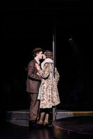 Ein Schauspieler und eine Schauspielerin stehen eng zusammen und küssen sich. Beide tragen Kleidung im Stil der 1930er Jahre. Ein Schauspieler und eine Schauspielerin stehen eng zusammen und küssen sich. Beide tragen Kleidung im Stil der 1930er Jahre.