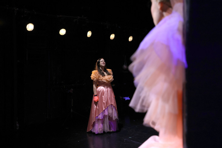 Eine Schauspielerin in einem bauschigen Kleid steht auf der Bühne. Eine Schauspielerin in einem bauschigen Kleid steht auf der Bühne.