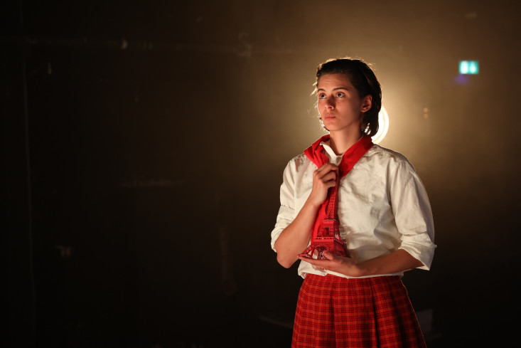 Eine Schauspielerin trägt einen roten Rock, eine weiße Bluse und ein rotes Halstuch. In den Händen hält sie eine kleine Eiffelturm-Skulptur. Eine Schauspielerin trägt einen roten Rock, eine weiße Bluse und ein rotes Halstuch. In den Händen hält sie eine kleine Eiffelturm-Skulptur.