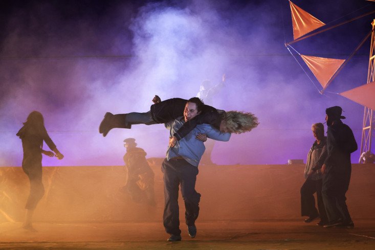Ein Schauspieler hat eine Schauspielerin über seine Schultern gelegt. Sie drehen sich, ihre Haare fliegen. Auf der Bühne ist Nebel. Ein Schauspieler hat eine Schauspielerin über seine Schultern gelegt. Sie drehen sich, ihre Haare fliegen. Auf der Bühne ist Nebel.