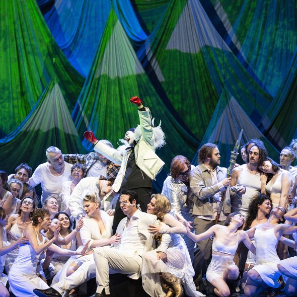 Das Rheingold  | Das Rheingold Eine Szeneimpression aus RHEINGOLD. Im Hintergrund ein Gebirge, davor umtanzen die Götter und Göttinnen gemeinsam mit den Flüchtenden Loge. Er dirigiert die ganze Bewegung.